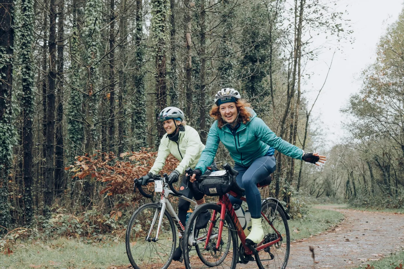 Hermione cycling with a friend through autumn woodland on the Ride the Change ride